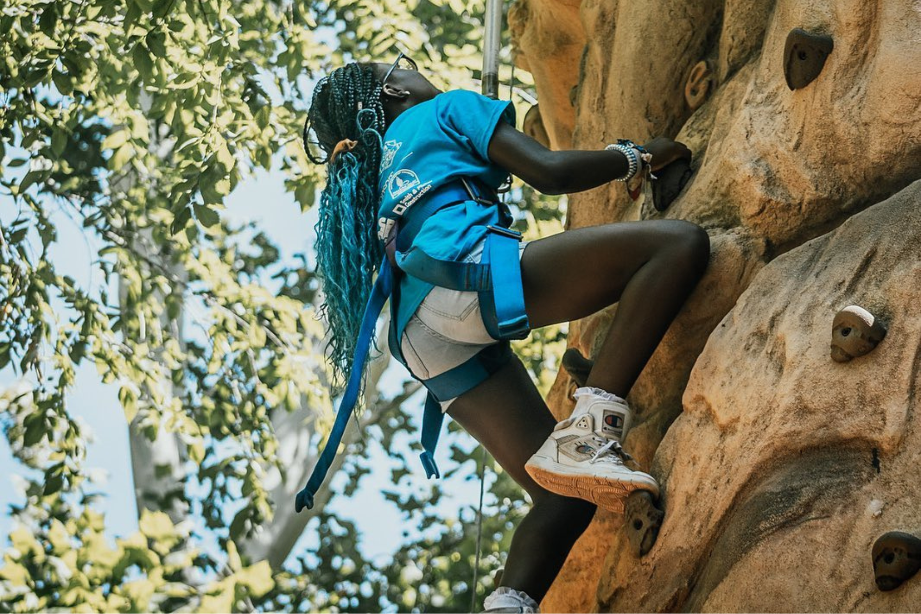 A young person climbs a rock wall