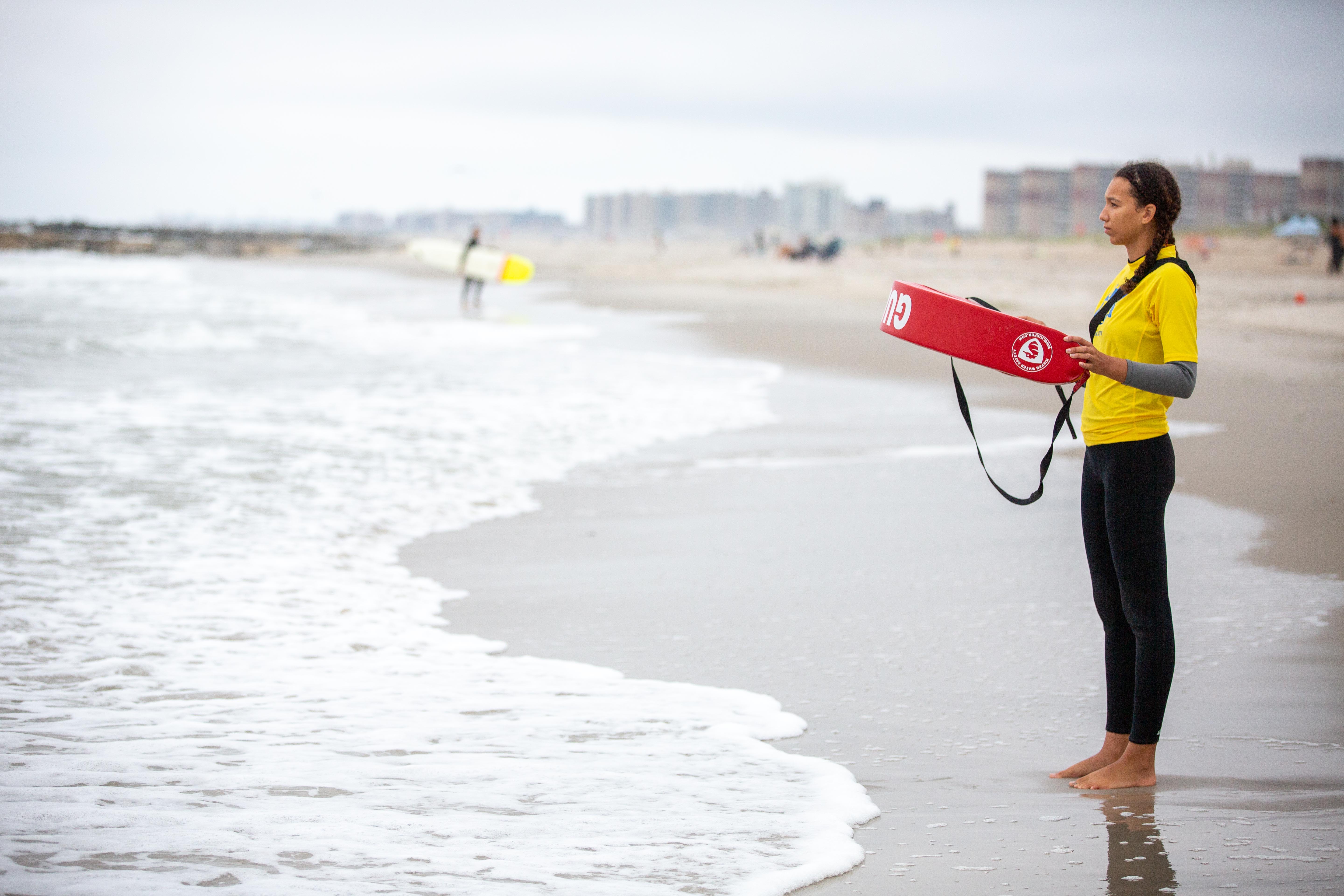 A person stands with a lifeguard aid next to the ocean