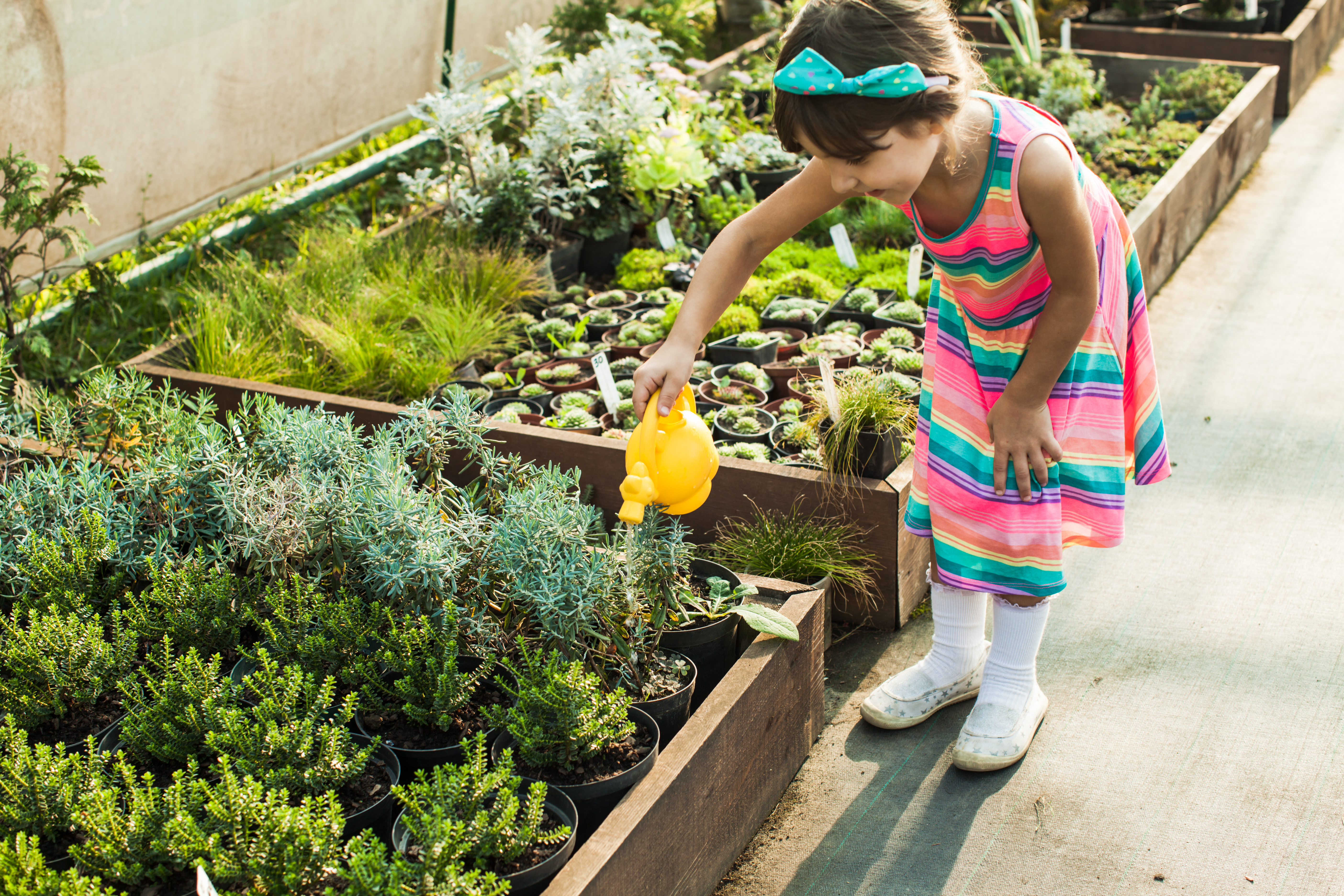 A child waters plants in a planter