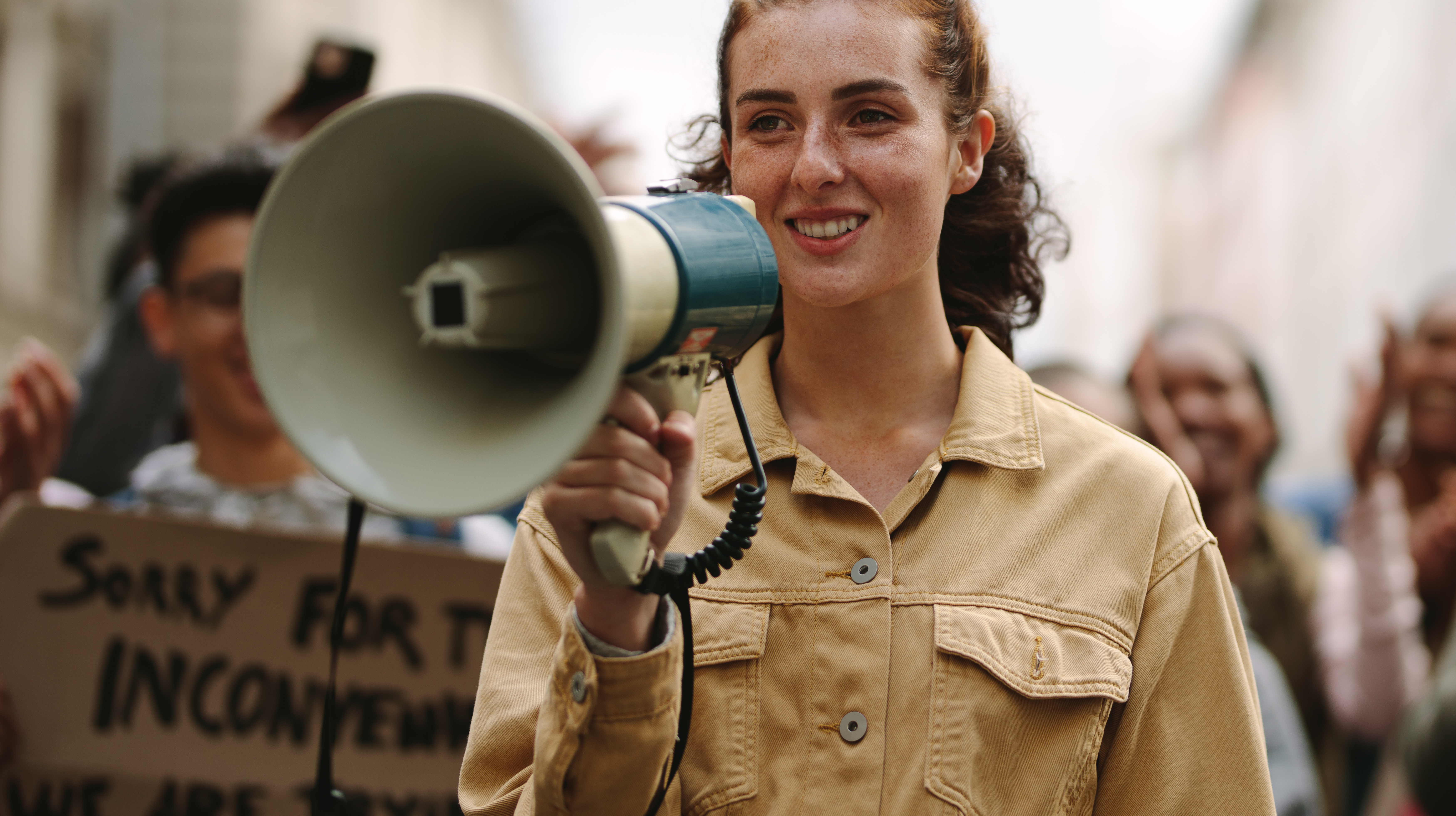 A teenager stands at the front of a crowd with a megaphone