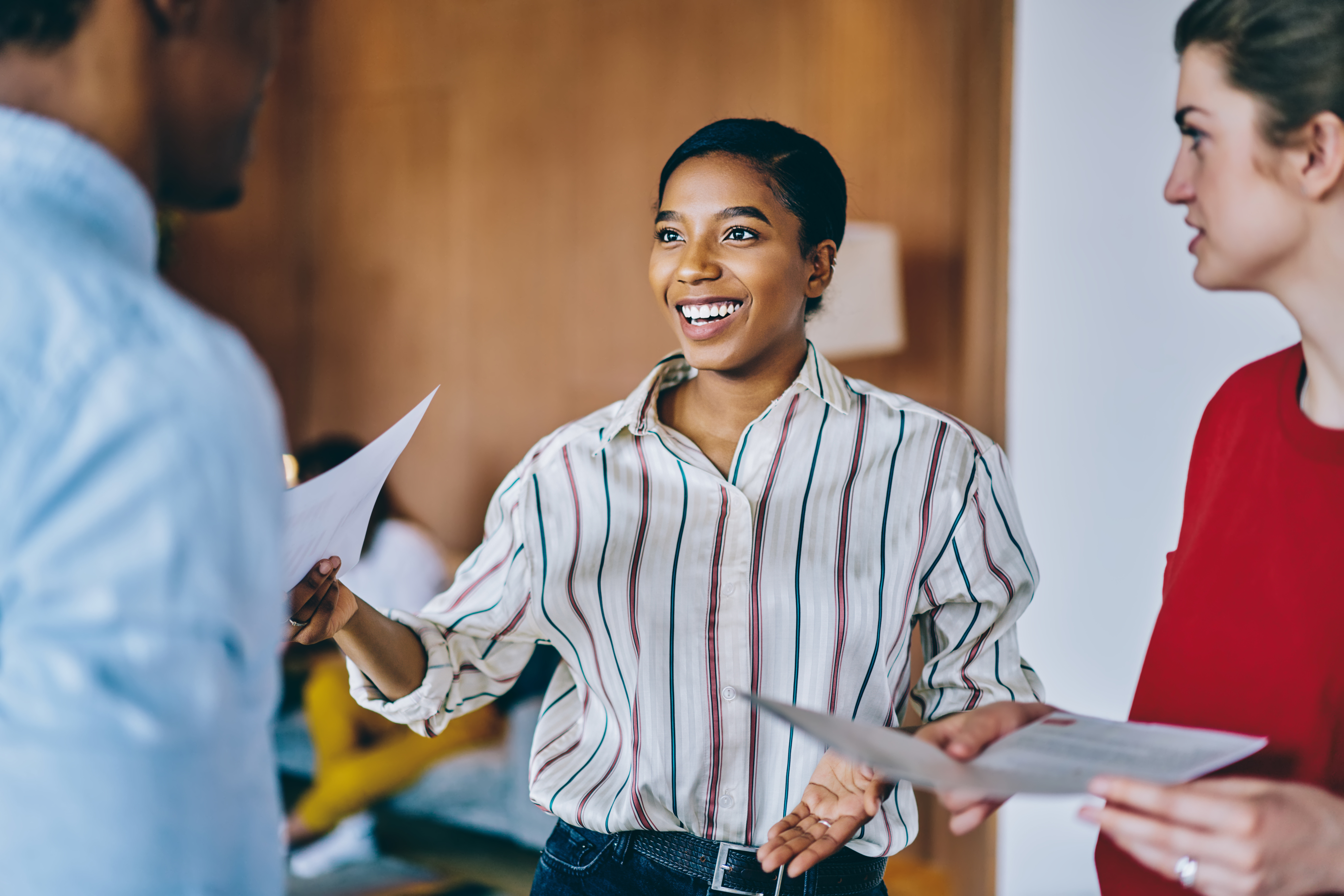 A woman stands talking to others and handing them papers