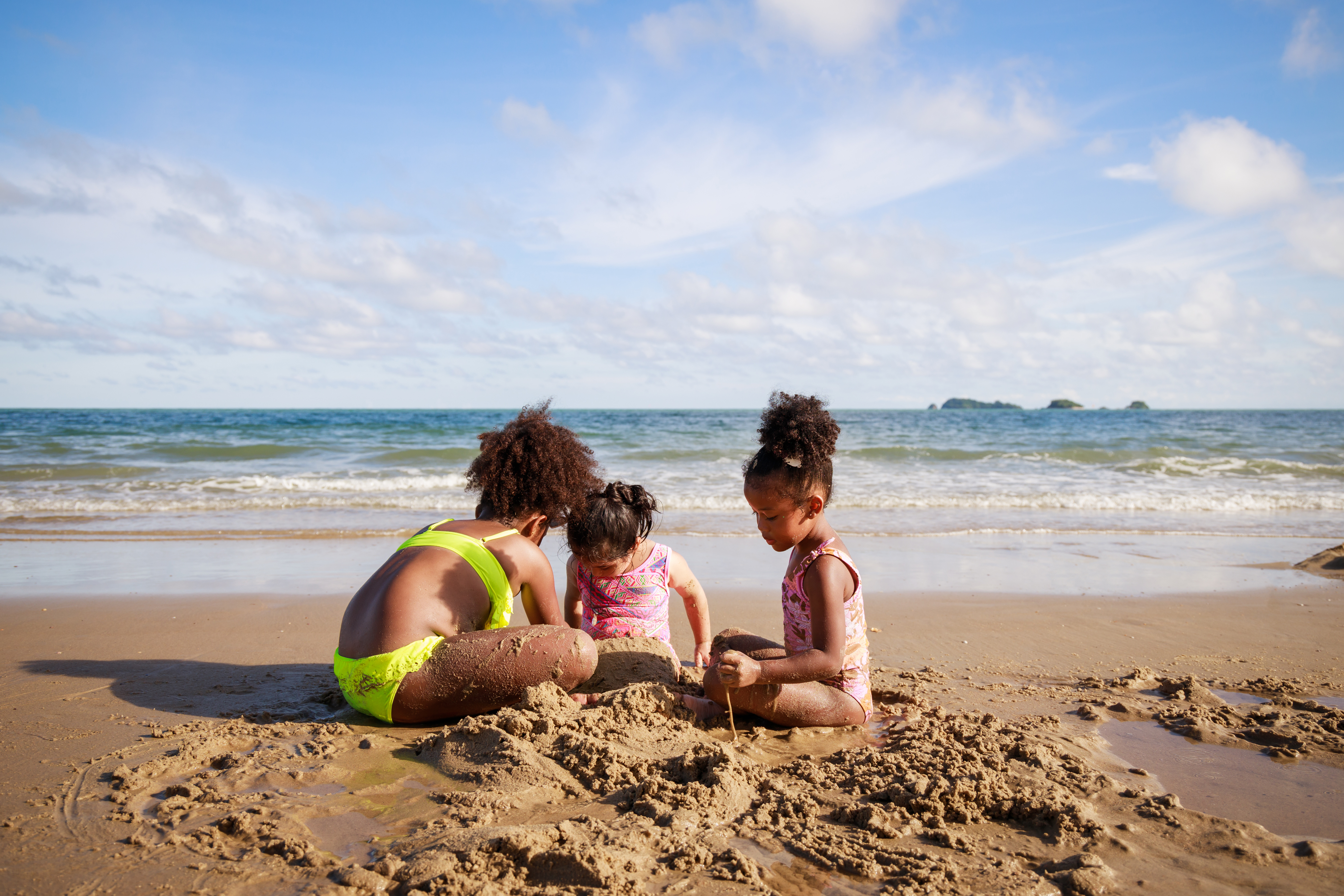 A group of kids play in the sand at the beach