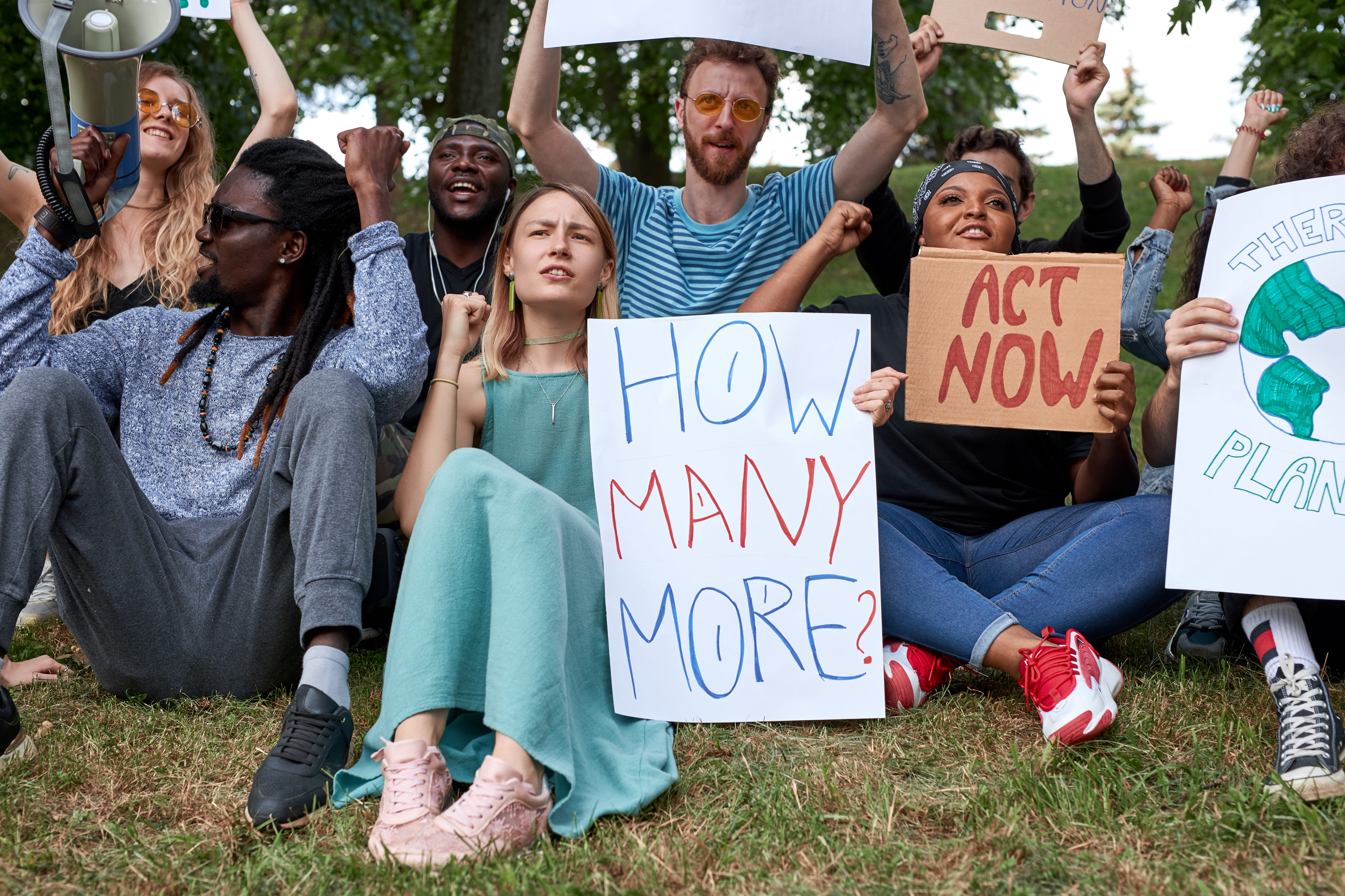 A group of young people sit holding signs about environmental action