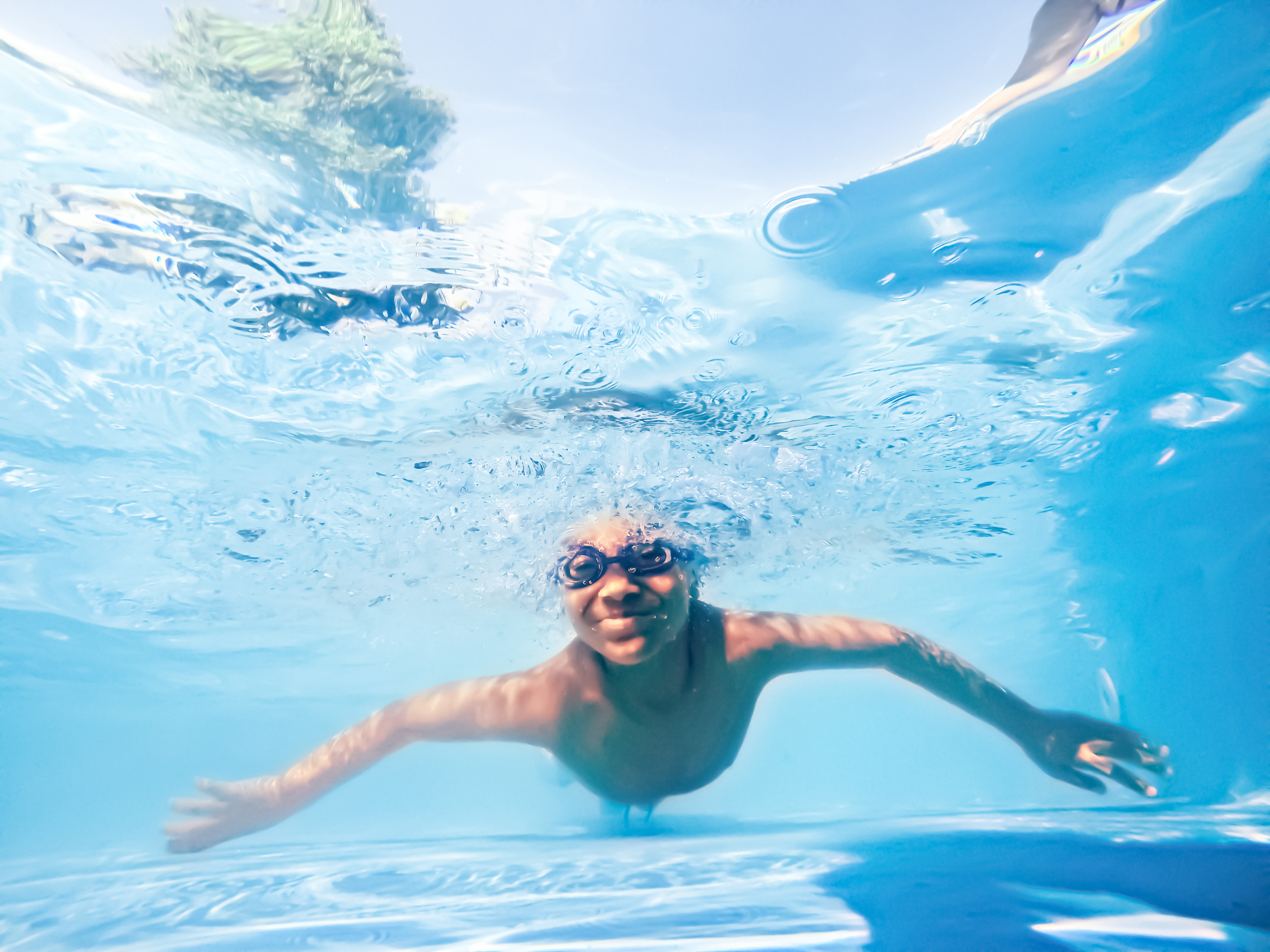 A child swims underwater while wearing goggles