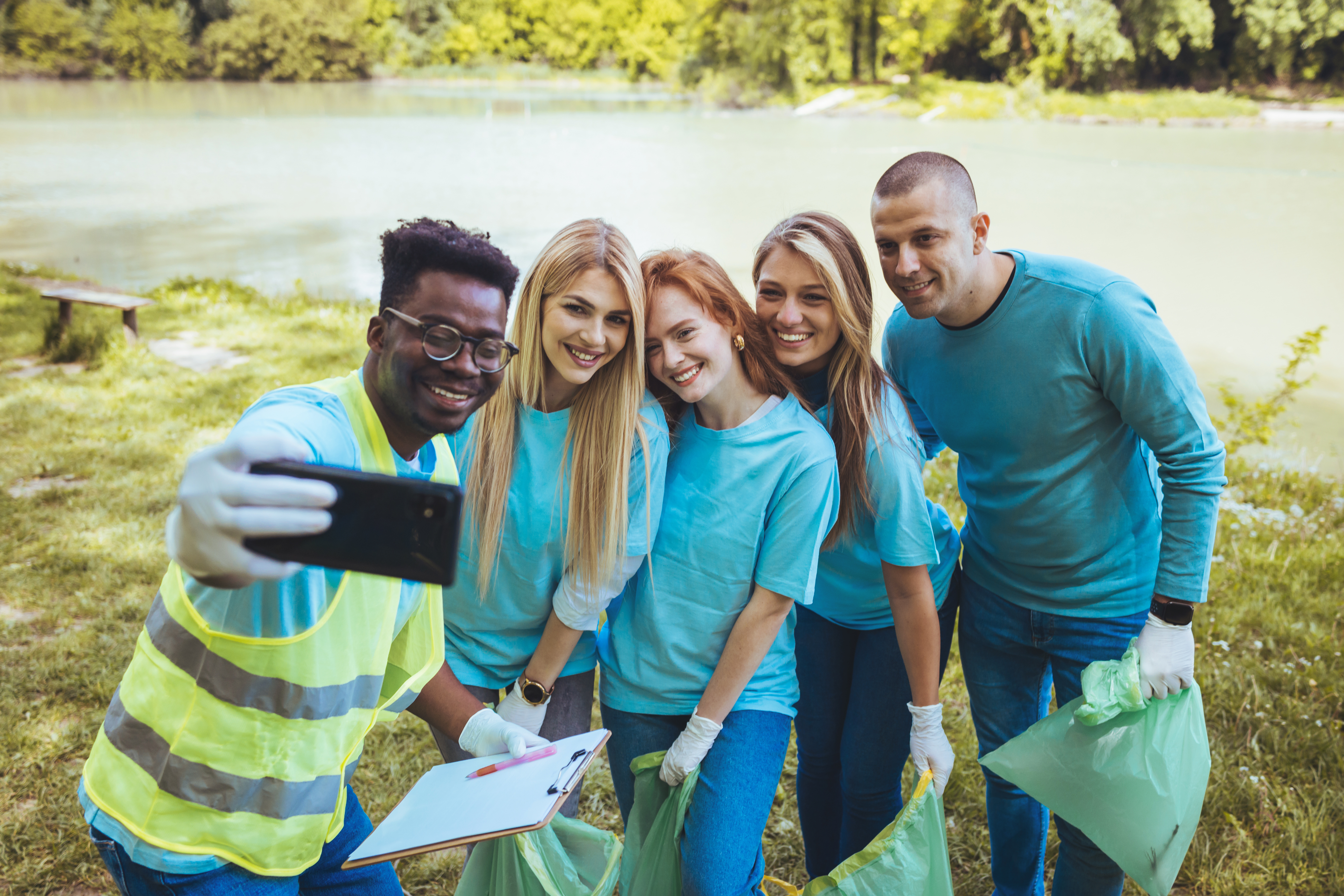 A group of people pose together for a selfie while picking up trash