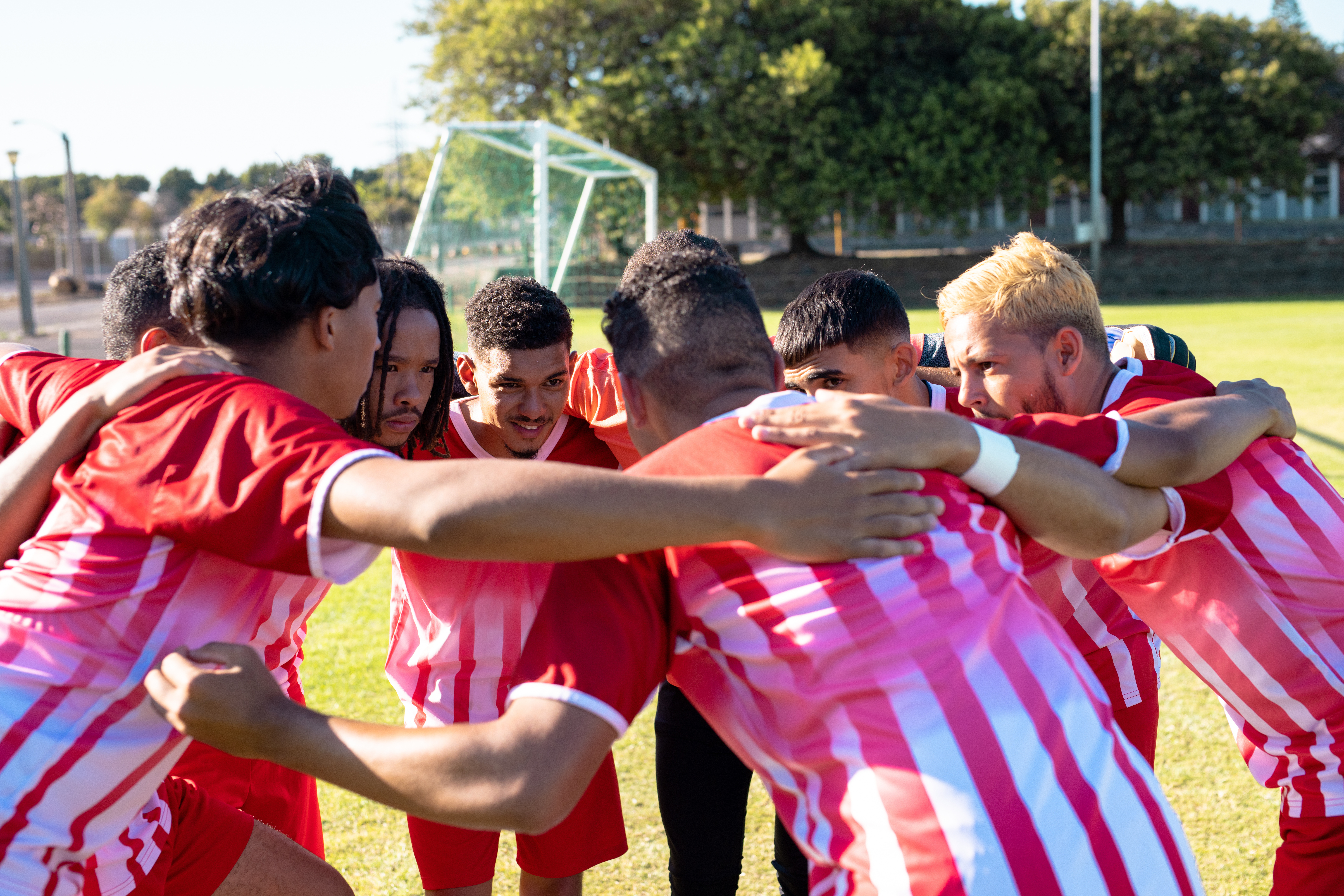 A soccer team huddles up in the middle of a field