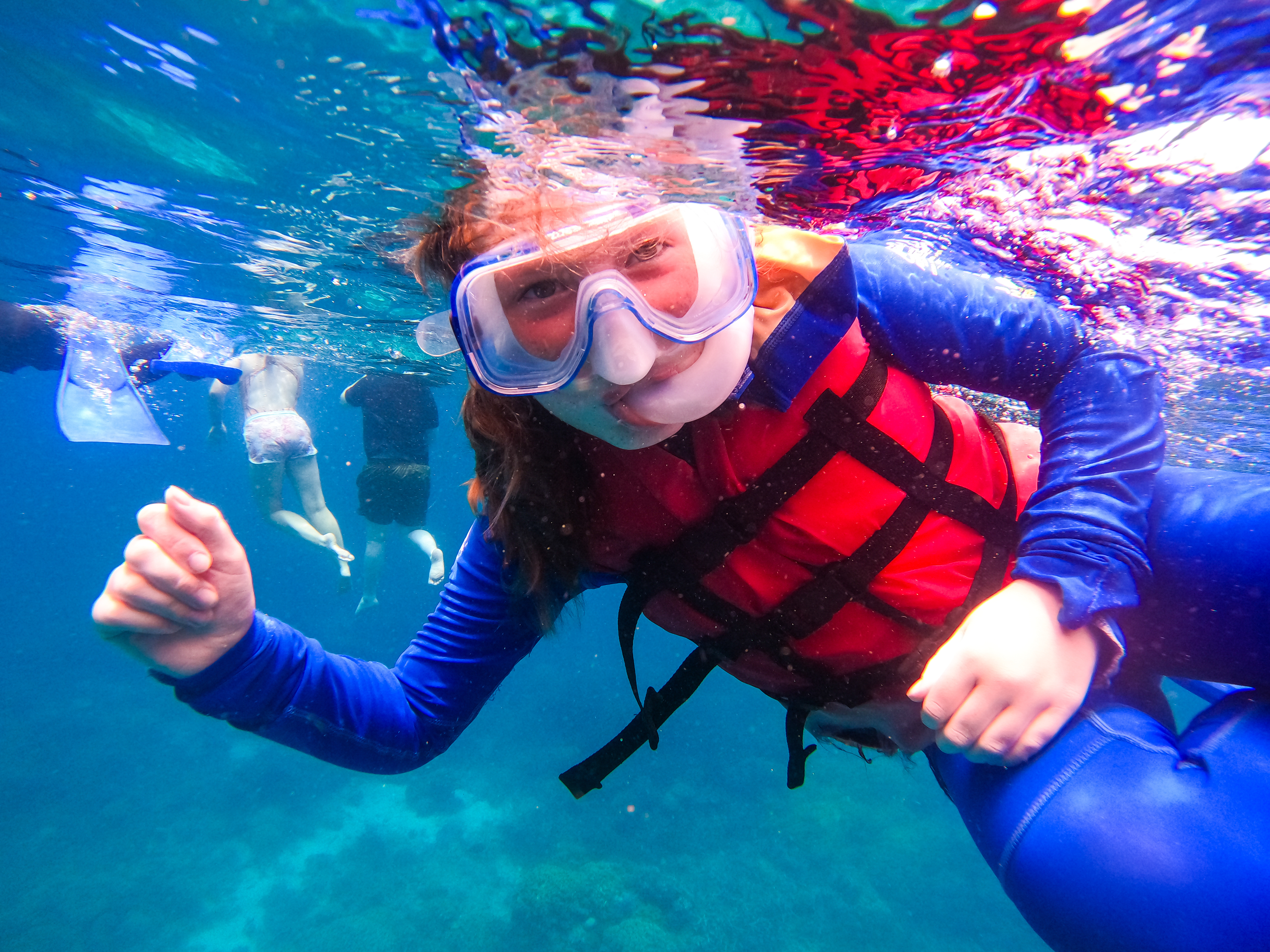 A child looks underwater with a snorkel and mask