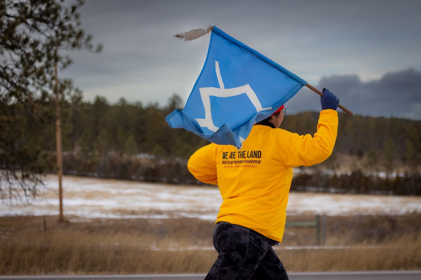 A young person runs while holding a blue flag