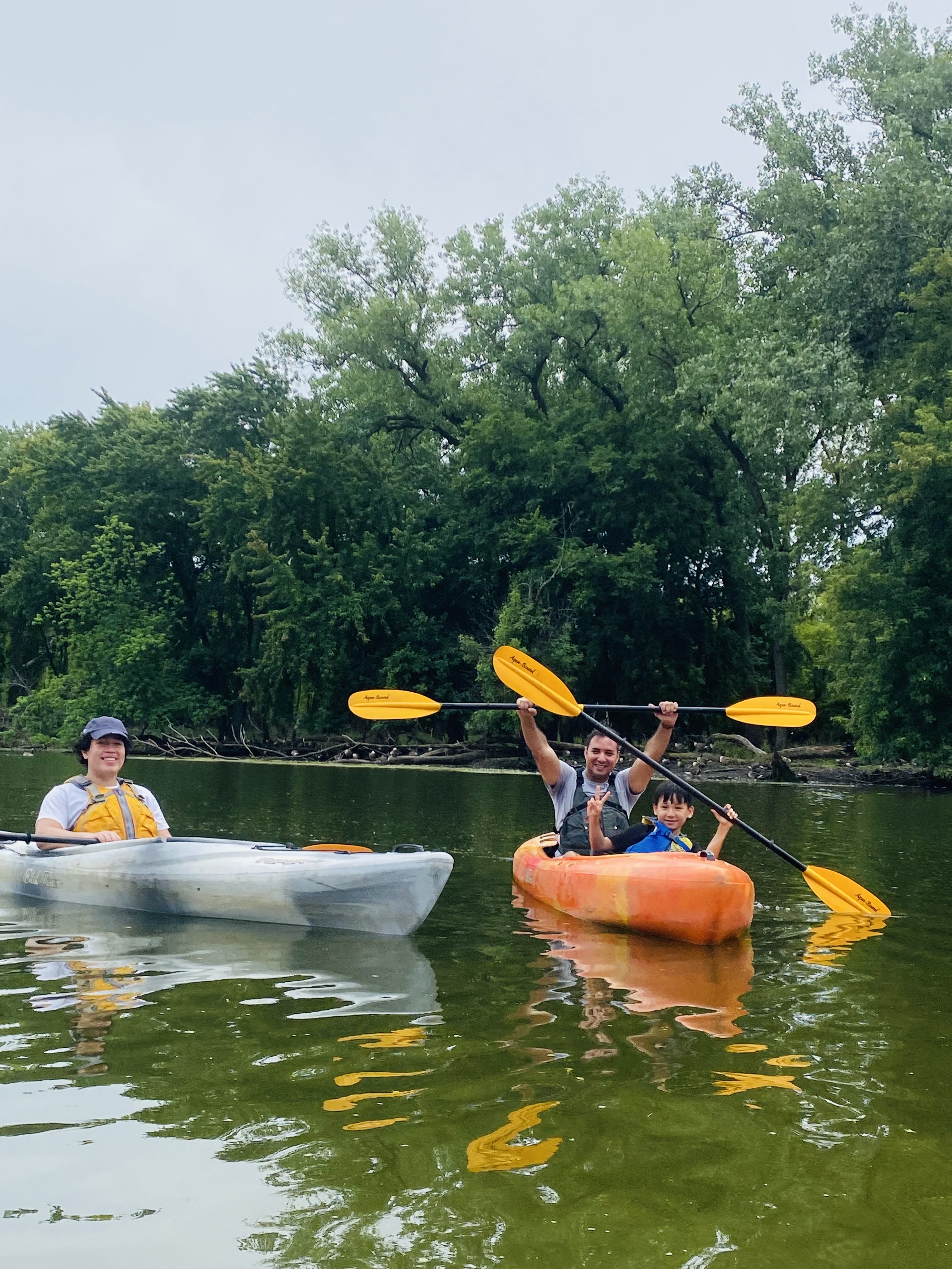 Adults and children sit in kayaks holding paddles